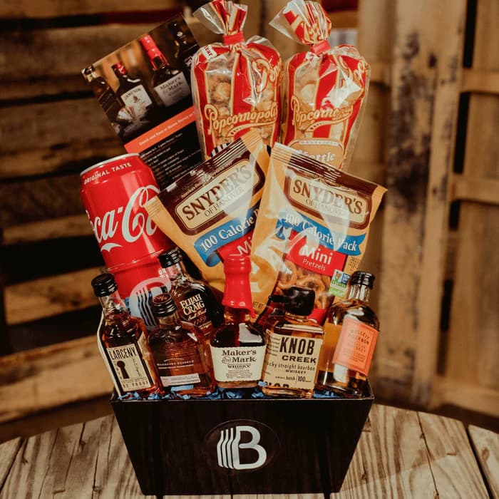 A Bite of Bourbon gift basket with bourbon minis, popcorn, pretzels, and snacks in a wooden crate