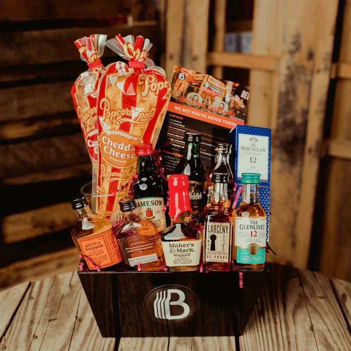 The Ultimate Whiskey Sampler gift with bourbon, Scotch, and Irish whiskey minis, a glass, and snacks in a crate